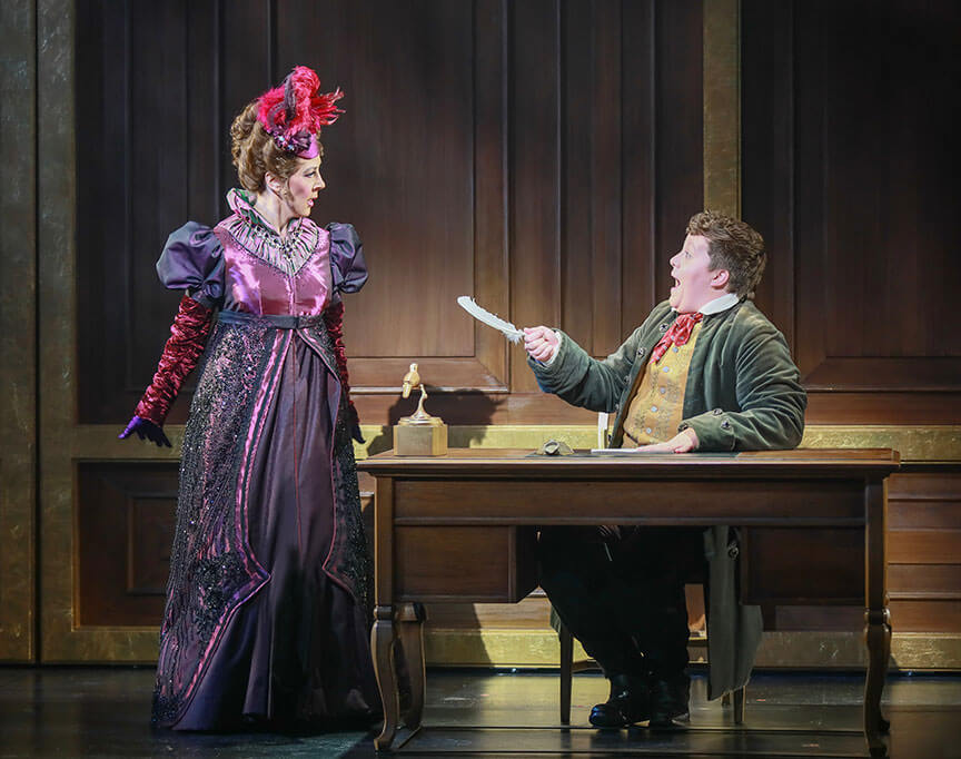 Janine LaManna as Lady Catherine confronts Sav Souza as Scutter across a desk in Regency Girls, 2025.