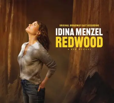 Promotional image for the original Broadway cast recording of Redwood, a new musical starring Idina Menzel. Idina stands among towering redwood trees, gazing upward with a serene expression, wearing a casual gray shirt and jeans. The title text "IDINA MENZEL REDWOOD" appears boldly in white and yellow on the right side.